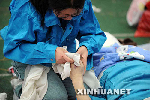 5月14日，張關(guān)蓉在擦拭丈夫譚千秋的遺體。 受汶川地震影響，四川省德陽(yáng)市東汽中學(xué)教學(xué)樓坍塌。在地震發(fā)生的一瞬間，該校教導(dǎo)主任譚千秋雙臂張開(kāi)趴在課桌上，身下死死地護(hù)著4個(gè)學(xué)生，4個(gè)學(xué)生都獲救了，譚老師卻不幸遇難。 新華社記者王建華攝